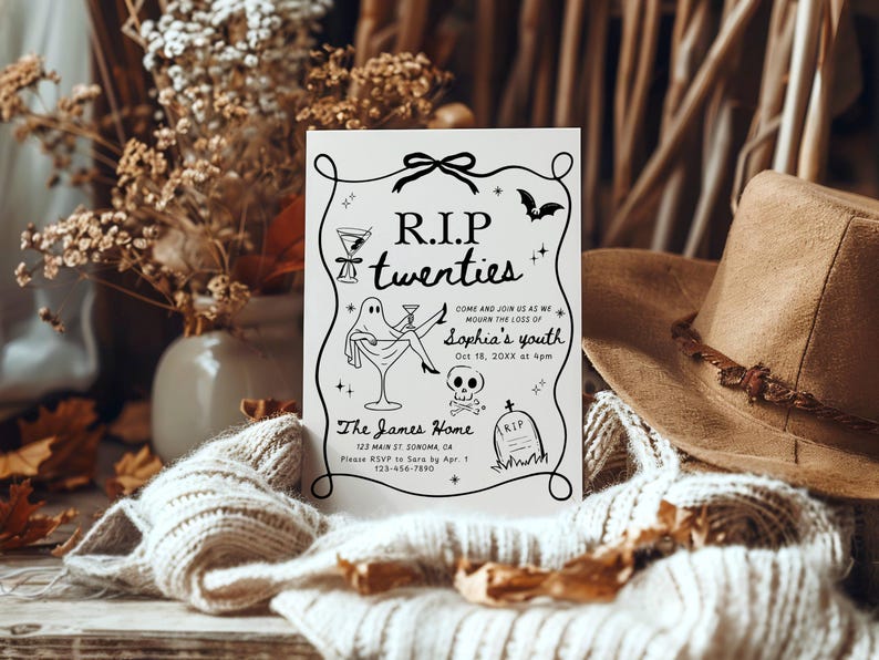 May include: A white invitation card with black text and illustrations for a "R.I.P. twenties" party. The card features a ghost, cocktail glasses, a bat, and a skull. A brown hat and dried flowers are in the background.