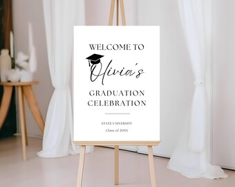 Può includere: Un cartello rettangolare bianco per la laurea su un cavalletto di legno con testo nero che recita WELCOME TO Olivia's GRADUATION CELEBRATION, STATE UNIVERSITY e Class of 20XX, con un'icona di tocco nero sopra il nome.
