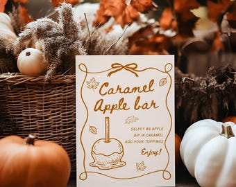 Puede incluir: Un letrero rectangular blanco con un borde dorado y el texto Caramel Apple bar, Select an apple, Dip in caramel, Add your toppings, Enjoy! El letrero presenta un dibujo lineal de una manzana de caramelo y pequeños iconos de hojas.