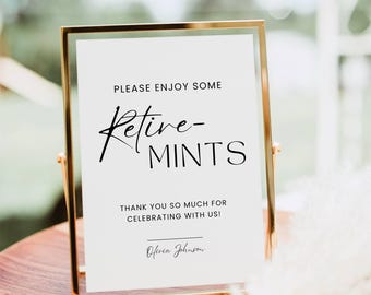 May include: A vertical rectangular sign in a gold metal frame featuring black text that reads: PLEASE ENJOY SOME Retive-MINTS THANK YOU SO MUCH FOR CELEBRATING WITH US! and the name Olivia Johnson written in a cursive script at the bottom.