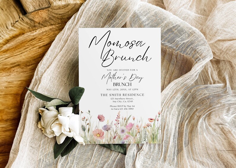 Op de afbeelding: Een witte kaart met zwarte tekst die een brunch voor Moederdag aankondigt. De tekst luidt "Momosa Brunch", "U bent uitgenodigd voor een brunch voor Moederdag", "12 mei 20XX, om 12:00 uur", "The Smith Residence", "125 Anywhere Street", "Any City, Ga, 12345", "RSVP graag v&oacute;&oacute;r 1 mei bij Sara op 123-456-7890". De kaart heeft een aquarelillustratie van roze en paarse bloemen.