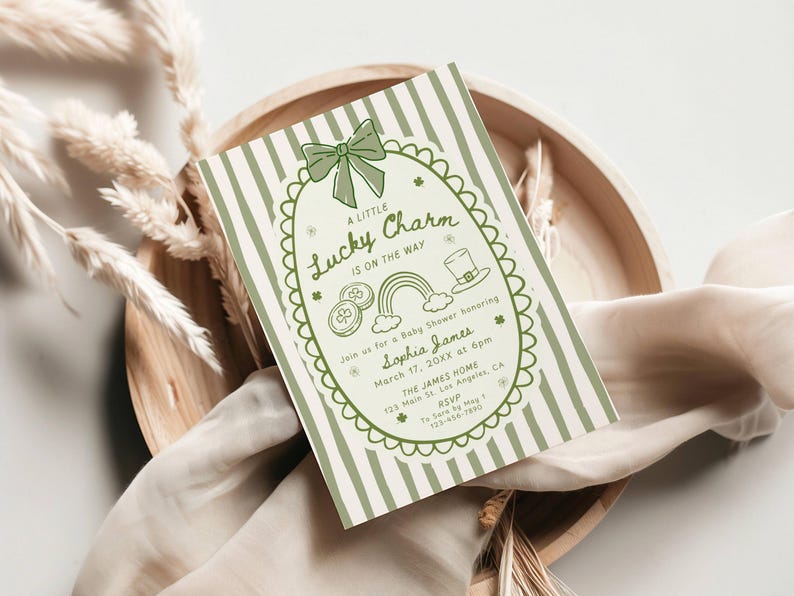 May include: A St. Patrick's Day baby shower invitation with a green and white striped background. The invitation features a green bow, shamrocks, a rainbow, and the text "A Little Lucky Charm Is On The Way."