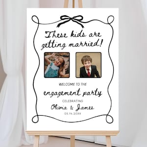 Op de afbeelding: Een wit bord met zwarte letters dat een verlovingspartij aankondigt. Het bord zegt "Deze kinderen gaan trouwen!" en toont foto's van een jong meisje en een jonge jongen. De tekst zegt ook "Welkom op het verlovingsparty ter ere van Olivia & James 05.14.20XX".
