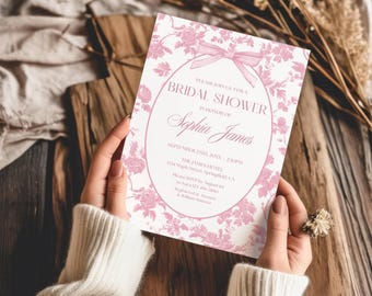 Puede incluir: Una tarjeta de invitación rectangular para despedida de soltera con un patrón floral rosa y un marco ovalado central con un lazo rosa. El texto dice: Please join us for a bridal shower in honor of Sophia James, September 23th, 20XX, 2:30PM.