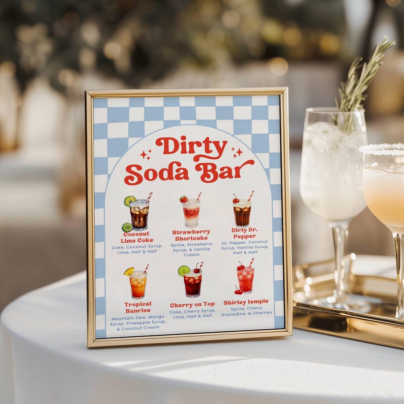 May include: A framed sign with a gold border displays a "Dirty Soda Bar" menu. The menu features six colorful drink illustrations with ingredients listed below each. Two cocktails in stemmed glasses are visible to the right.