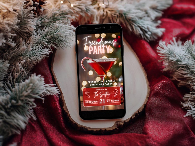 May include: A smartphone displaying a digital invitation for a Friendsmas party. The invitation features a festive red cocktail with a candy cane garnish and the text "Friendsmas Party" in neon pink letters. The text also includes the date and time of the party: December 21 at 4:00 PM.