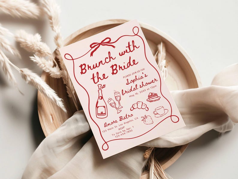 May include: A pink bridal shower invitation with red text that reads "Brunch with the Bride" and includes details for Sophia's bridal shower. The invitation features illustrations of champagne, pastries, and a strawberry.