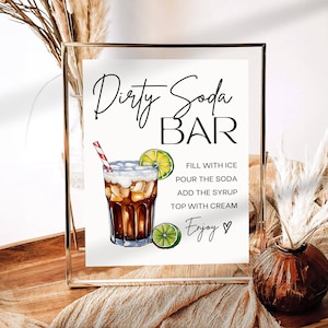 May include: A printable sign for a "Dirty Soda Bar" with instructions on how to make the drink. The sign features a hand-drawn illustration of a glass of dirty soda with a lime wedge and a red and white striped straw.