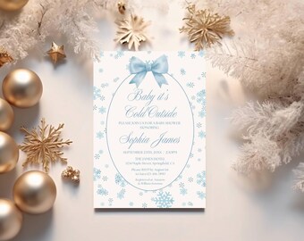 May include: A rectangular baby shower invitation card featuring a light blue bow at the top of an oval frame. The text reads: Baby it's Cold Outside, PLEASE JOIN US FOR A BABY SHOWER HONORING Sophia James, SEPTEMBER 27TH, 20XX, 2:30PM.