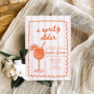 May include: A pink and white striped invitation with the words "a spritz older" in orange script. The invitation includes details for a birthday party, featuring a cocktail illustration.