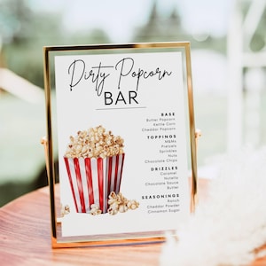 May include: A gold-framed sign with the text "Dirty Popcorn BAR" and a list of popcorn toppings, drizzles, and seasonings. A red and white striped popcorn container is illustrated on the sign, filled with popcorn.