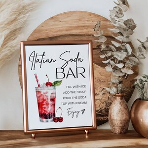 Op de afbeelding: Een printbaar bord voor een "Hatian Soda Bar" met een aquarel-illustratie van een glas soda met kersen en een rietje. Het bord bevat instructies voor het maken van de drank: "Vul met ijs, voeg de siroop toe, giet de soda, top met room, Geniet."