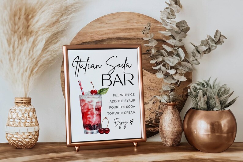 Op de afbeelding: Een printbaar bord voor een "Hatian Soda Bar" met een aquarel-illustratie van een glas soda met kersen en een rietje. Het bord bevat instructies voor het maken van de drank: "Vul met ijs, voeg de siroop toe, giet de soda, top met room, Geniet."