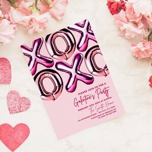 May include: Pink Galentine's Party invitation with foil balloon-style "XOXO" design. The invitation includes event details: date, time, and location. Decorative pink hearts and flowers surround the invitation on a marble surface.