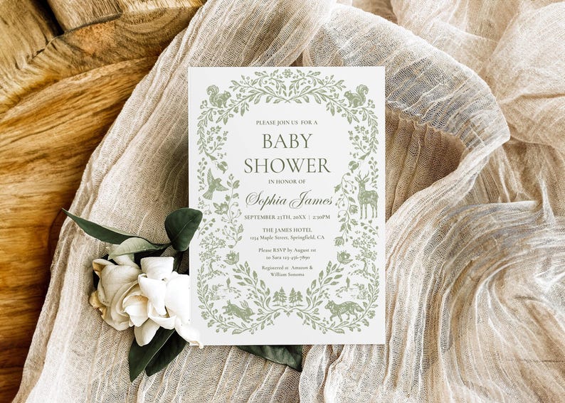 May include: A baby shower invitation with a green floral border and forest animal illustrations. The invitation includes the text "Baby Shower" and the name "Sophia James". The invitation is on a white background, with a beige fabric and white flowers.