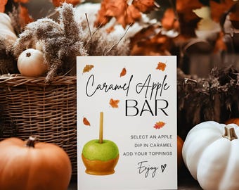 Puede incluir: Un letrero rectangular blanco con el texto Caramel Apple Bar, Select an apple, Dip in caramel, Add your toppings y Enjoy. El letrero presenta una ilustración de una manzana verde con una base de caramelo y hojas de otoño naranjas.