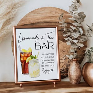 May include: A framed sign with the text "Lemonade & Tea BAR" and instructions for making the drinks. The sign features watercolor illustrations of iced tea and lemonade. Decorative vases and plants are in the background.
