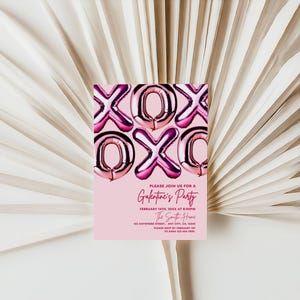May include: A pink invitation card with the text "XOX" in metallic pink balloon letters. The card reads "Please join us for a Galentine's Party" with event details. The card is set against a backdrop of white, textured palm leaves.