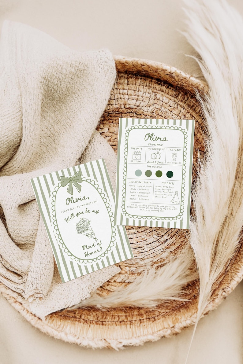 May include: Two invitation cards with green and white striped backgrounds. One card reads "Olivia, Will you be my Maid of Honor?" The other card has wedding details. The cards are on a woven tray with a beige cloth and a feathery plant.