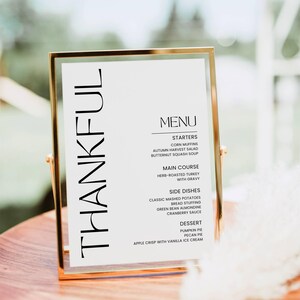 May include: A gold-framed menu with the word "THANKFUL" printed vertically on the left side. The menu lists a Thanksgiving dinner with starters, main course, side dishes, and dessert.