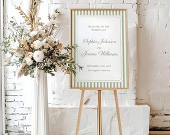 Puede incluir: Un letrero de bienvenida de boda rectangular en un marco de madera clara, con rayas verticales de color verde salvia y texto blanco: Welcome to the wedding of Sophia Johnson and James Williams, September 21st, 20XX, Los Angeles, California.