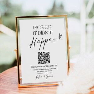 May include: A white sign in a gold frame with the text "Pics or it didn't happen" and a QR code. The text "Share your photos with us" is below the QR code, followed by instructions to scan the code with a smartphone and upload photos. The names "Olivia & James" are at the bottom of the sign.