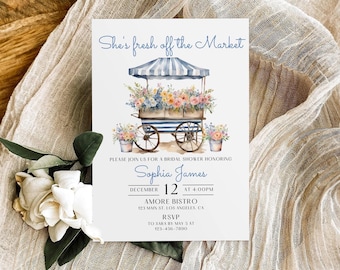 Op de afbeelding: Een witte uitnodigingskaart voor een bruidsdouche met een aquarelillustratie van een blauw-wit gestreepte bloemenkar vol kleurrijke bloemen. De tekst luidt: She's fresh off the Market, Please join us for a bridal shower honoring Sophia James, December 12 at 4:00PM, Amore Bistro, 123 Main St. Los Angeles, CA, RSVP to Sara by May 5 at 123-456-7890.