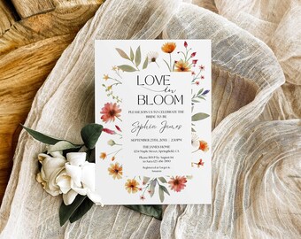 May include: A rectangular wedding invitation card featuring a watercolor floral wreath in shades of orange, pink, and green. The text reads LOVE IN BLOOM, PLEASE JOIN US TO CELEBRATE THE BRIDE TO BE, Sophia James, SEPTEMBER 23TH, 20XX, 2:30PM.