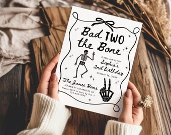 Peut inclure: Une carte d'invitation d'anniversaire rectangulaire blanche avec du texte et des illustrations en noir. La carte indique Bad TWO the Bone, Sophia's 2nd birthday, October 18, 20XX, The James Home, 123 Main St. Los Angeles, CA, et les détails RSVP.