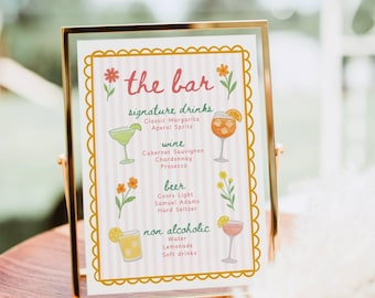 May include: A rectangular gold metal frame holds a menu sign with a light pink and white striped background. The sign features the text the bar, signature drinks, wine, beer, and non alcoholic, decorated with colorful floral and drink illustrations.
