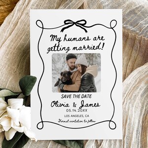 May include: Save the date card with a black and white photo of a couple and their dog. The text reads "My humans are getting married!" "Olivia & James" "05.14.20XX" "Los Angeles, CA" "Formal invitation to follow."