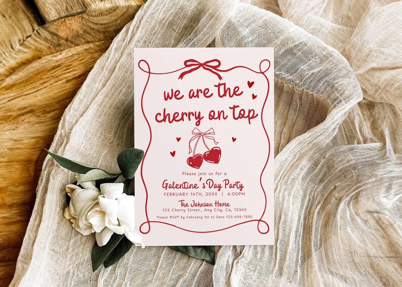 May include: A Valentine's Day party invitation with the text "we are the cherry on top" in red script. The invitation features a cherry design and is on a light pink background. White flowers and fabric are in the background.