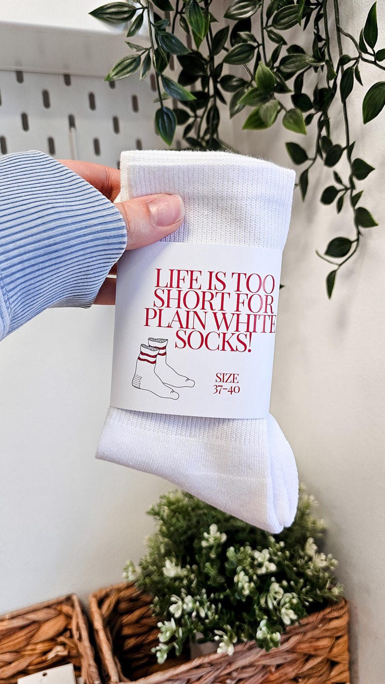 Peut inclure: Des chaussettes blanches avec des rayures rouges et blanches. L'emballage indique "La vie est trop courte pour les chaussettes blanches simples !" et "Taille 37-40".