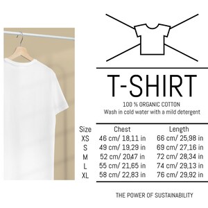 May include: A white T-shirt made of 100% organic cotton hangs on a wooden hanger. The image includes a size chart with chest and length measurements in both centimeters and inches. The text on the image reads "T-SHIRT".