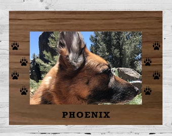May include: A wooden photo frame with a paw print border. The frame has a photo of a brown and black dog with the name "PHOENIX" printed below the photo.