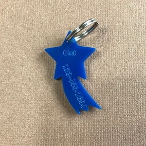 May include: Blue star-shaped pet ID tag with a silver key ring. The tag has the word "Cat" and the phone number "123-456-7890" engraved on it.