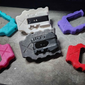 May include: A collection of colourful plastic handles and bases. The handles are teal, pink, purple, and red. Two bases feature cassette tape designs, one white and one grey.