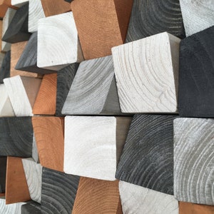 May include: A geometric wall art piece made of wood blocks in various shades of brown, gray, and black. The blocks are arranged in a staggered pattern, creating a visually interesting and modern design.