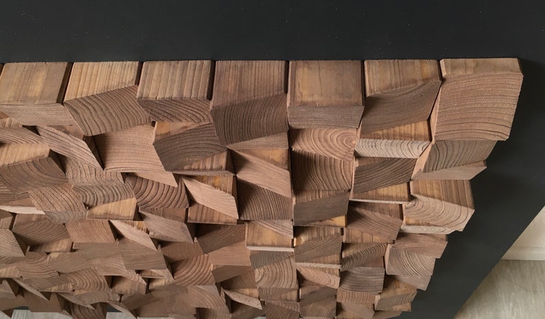 Puede incluir: Una pieza de arte de pared hecha de madera con un dise&ntilde;o geom&eacute;trico. La madera es de color marr&oacute;n claro y las piezas est&aacute;n dispuestas en un patr&oacute;n aleatorio.