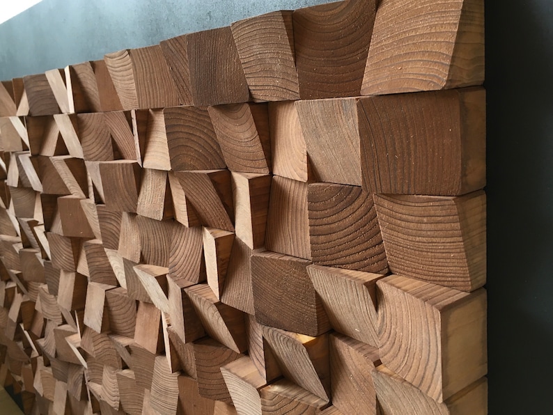 Puede incluir: Una pieza de arte de pared hecha de bloques de madera en varias formas y tama&ntilde;os. Los bloques est&aacute;n dispuestos en un patr&oacute;n geom&eacute;trico, creando un aspecto texturizado y moderno. La madera es de color marr&oacute;n natural.