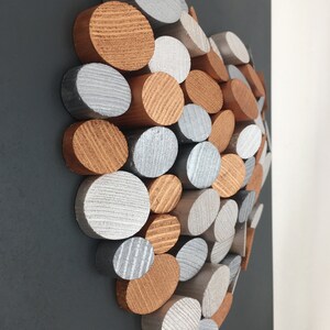 May include: A heart-shaped wall art piece made of wood circles in silver and copper tones. The circles are arranged in a random pattern, creating a unique and modern design.