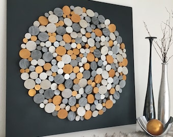 May include: A circular wall art piece made of wood rounds in shades of gray, silver, and gold. The rounds are arranged in a circular pattern on a dark gray background.