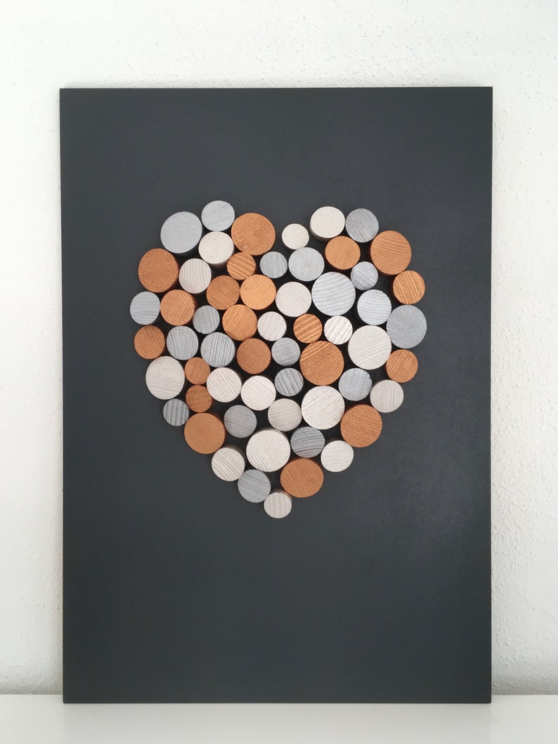 May include: A heart-shaped wall art piece made of wood rounds in shades of silver, white, and copper. The rounds are arranged in a heart shape on a black background.
