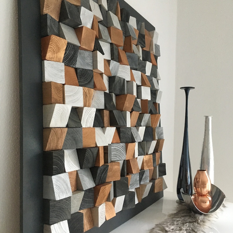 May include: A geometric wall art piece made of wood blocks in shades of gray, brown, and white. The blocks are arranged in a random pattern to create a modern and abstract design.