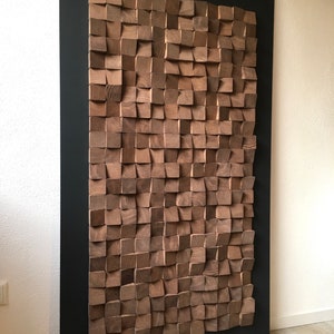 Puede incluir: Una gran pieza de arte de pared hecha de bloques de madera en un patr&oacute;n geom&eacute;trico. Los bloques est&aacute;n dispuestos en un patr&oacute;n de onda y est&aacute;n pintados en un color marr&oacute;n oscuro. El arte de pared est&aacute; enmarcado en un marco negro.