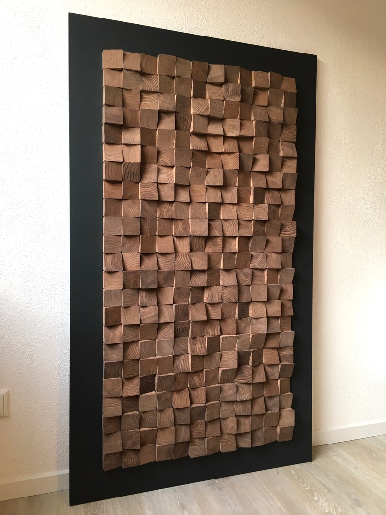 Puede incluir: Una gran pieza de arte de pared hecha de bloques de madera en un patr&oacute;n geom&eacute;trico. Los bloques est&aacute;n dispuestos en un patr&oacute;n de onda y est&aacute;n pintados en un color marr&oacute;n oscuro. El arte de pared est&aacute; enmarcado en un marco negro.