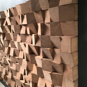 Puede incluir: Una pieza de arte de pared hecha de madera con un patr&oacute;n geom&eacute;trico. La madera es de color marr&oacute;n claro y las piezas est&aacute;n dispuestas en un patr&oacute;n escalonado.