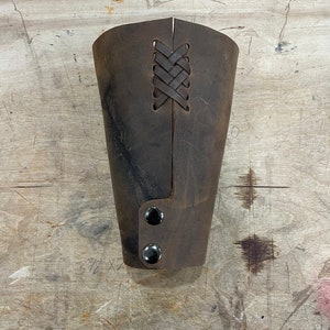 May include: A brown leather cuff with a braided strap detail and two black metal snaps.