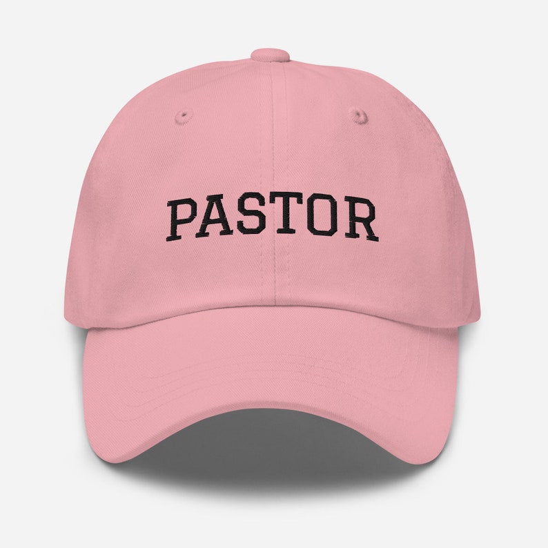 May include: A pink baseball cap with the word "PASTOR" embroidered in black on the front.
