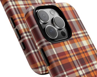 Puede incluir: Primer plano de dos fundas de teléfono con un patrón de cuadros en tonos marrón, naranja y crema. Las fundas del teléfono tienen un protector de lente negro. Las fundas están en ángulo, mostrando el diseño y la cámara del teléfono.